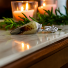 Mookaite jasper pendulum on marble beside a candle and greenery