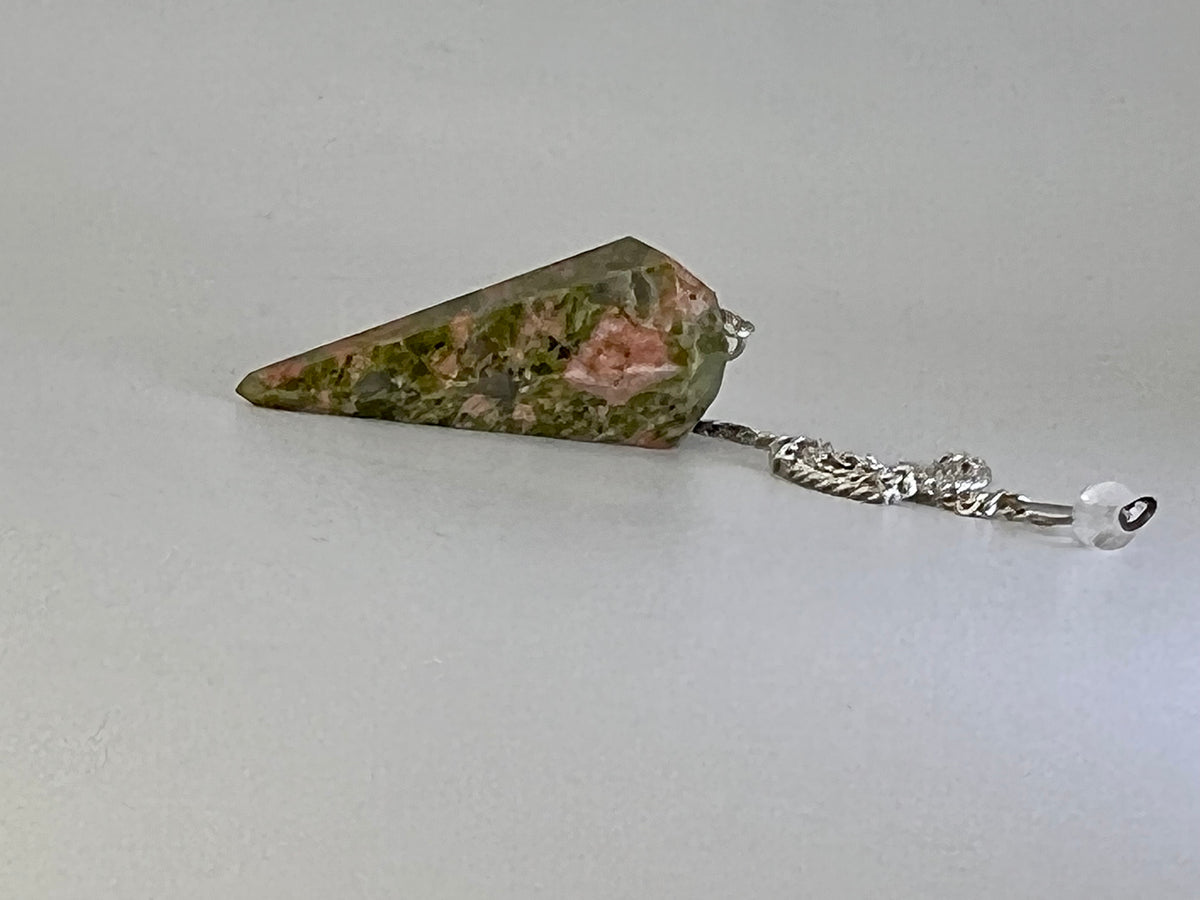 Green and pink unakite jasper pendulum on a silver chain against a light grey background