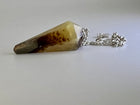 Mookaite jasper pendulum in cream and red tones on a silver chain, grey background