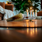 Mookaite jasper pendulum on a wooden table with candles