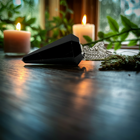 Black obsidian pendulum on a dark wooden table with candlelight