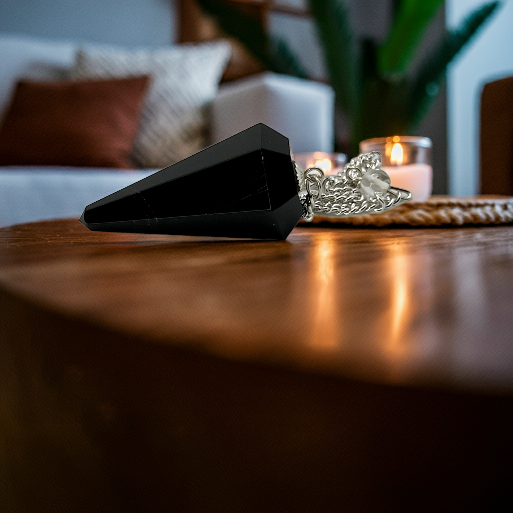 Black obsidian pendulum on a round wooden table