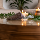 Rhodochrosite pendulum on a wooden table with candles and plants